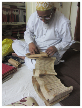 Figure 13.7: The Dāʿī carefully unrolling one of the oldest scrolls of the khizāna collection