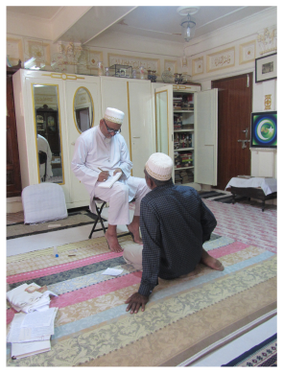 Figure 13.13: Left: The Dāʿī is writing a taʿwīdh for a believer during an audience in his office in the treasury of books. Right: boxes storing the various kinds of taʿwīdh in his office in Arabic, Gujarati, and Lisān al-daʿwa, the sociolect of the community