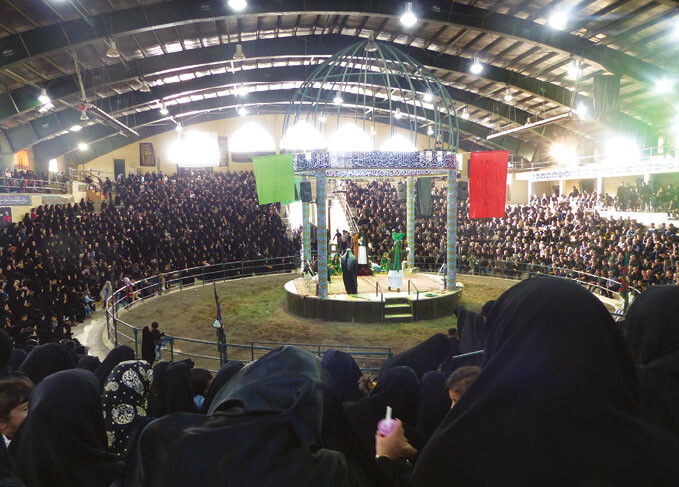 A crowded arena-style indoor performance space with a central domed platform