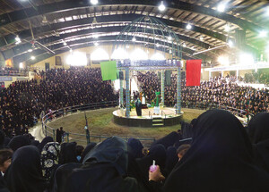 A crowded arena-style indoor performance space with a central domed platform