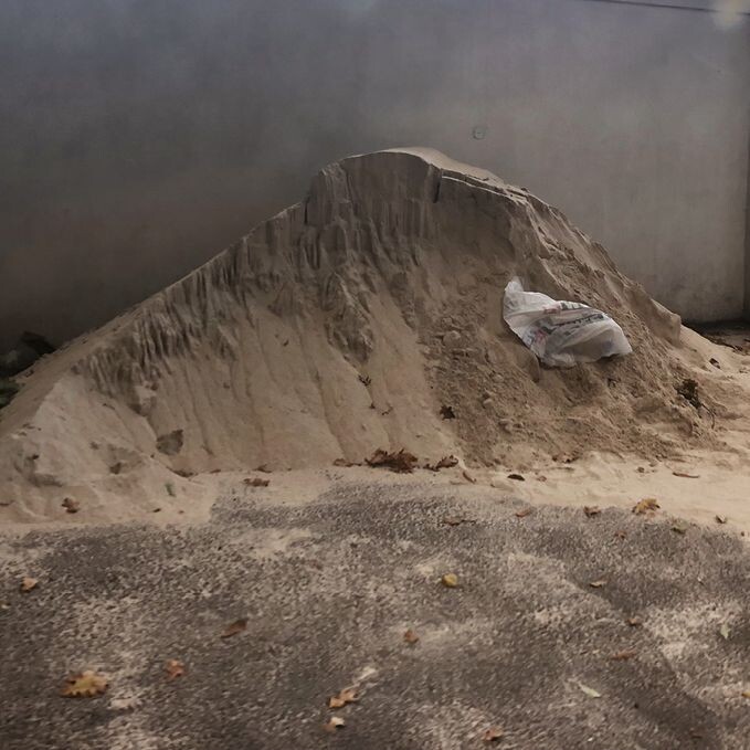 heap of sand with small torn white plastic bag