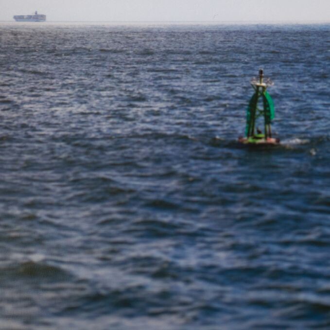 buoy-like object in open sea with a large ship at the horizon