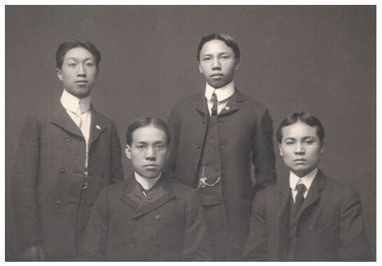 Four young Chinese men in dark Western suits and no queues, Liang Qichao wearing glasses.