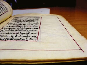 A side view of a manuscript containing Arabic text, showing diagonal lines that have been pressed in the paper.