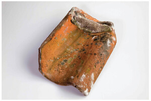 A picture of a red, ceramic rooftile from the sixteenth or seventeenth century