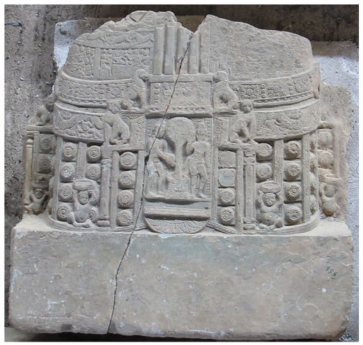 It depicts a miniature stūpa with intricate carving on the dome and the drum, although the upper portion of the stūpa is lost. A tree with two male attendants is placed at its entrance.