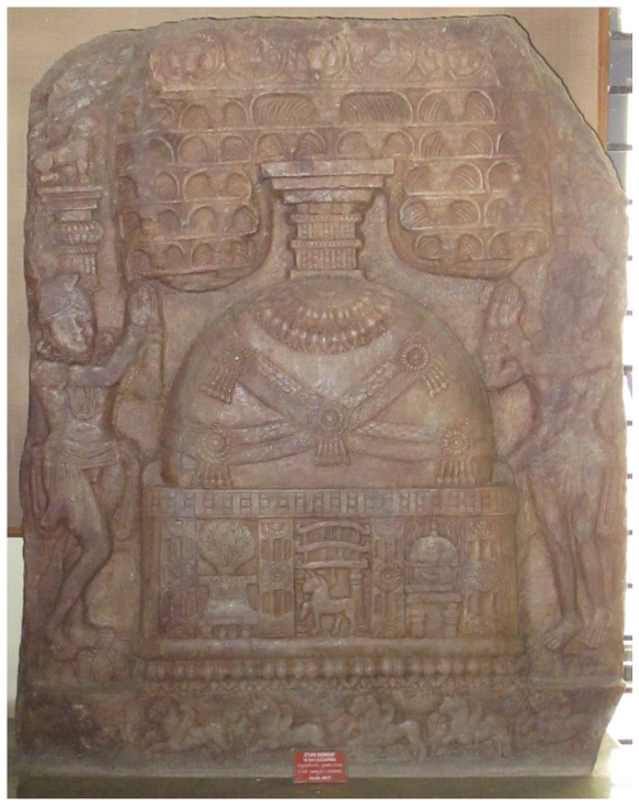 It depicts a miniature stūpa with sprouting umbrellas on the top. Two standing figures venerate the stūpa. The base section of the stūpa depicts a throne with a tree, a gateway with a horse, and a relic casket in three registers.