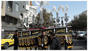 A man holds up an ornate ʿalāmat—a symbolic metal standard—while walking in an Ashura procession in Tehran, 2017.